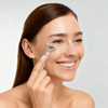 A stainless steel facial roller held by a smiling woman with long brown hair, featuring a sleek silver design.