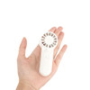 A portable handheld fan in white, fitting comfortably in a person's hand, featuring a circular grille and a button.