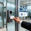 A business card being scanned at a glass door entry system, featuring a logo and a sleek design.