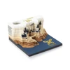 A 3D paper carving notepad in cream and blue featuring an intricate castle design atop a layered landscape.