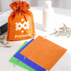 An orange non-woven drawstring bag with a logo, alongside a green and an orange square pouch on a table.