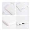 A white 5000mAh power bank with a built-in charging cable, featuring USB ports and a logo on the back.