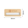 A wooden name badge, featuring a rectangular shape with a clear insert, and a logo. It's light brown in colour.