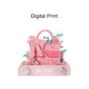 A pink 3D paper art handbag notepad, embellished with flowers and a bow, resting on a flat base with a logo.