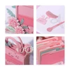 A pink 3D paper art handbag with floral details and various decorative cut-outs, featuring accessories like glasses and a comb.