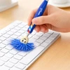 A blue Mop Topper Pen with a playful mop head is being used to clean a keyboard. The pen has a logo.