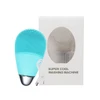 A silicone facial cleansing brush in teal, accompanied by a USB charging cable and packaging with a window.