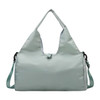 A light green duffle bag with a yoga mat strap, featuring a logo and adjustable shoulder strap.