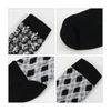 Four pairs of socks featuring different patterns, including a black and white design and an argyle pattern, with black sections.