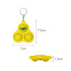 A yellow keychain with three poppable bubble-like buttons and a logo. Dimensions are 7.5 cm by 7 cm.