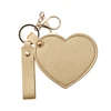 A heart-shaped compact mirror with a keychain, featuring a gold textured finish and a gold clasp.