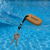 An oval cork keyring with a black attachment, floating in water with a set of keys.