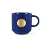 A ceramic mug in deep blue with ribbed texture and a bronze medal feature on the front.