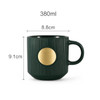 A green ceramic mug featuring a textured design and a bronze medal in the centre, with a capacity of 380ml.