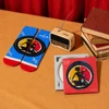 A red and blue pair of socks, a vintage radio, and two CDs in decorative cases on a table with books.