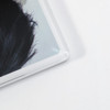 A close-up of a clear acrylic fridge magnet with a textured surface and a rounded corner.
