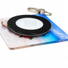 A black and clear NFC acrylic spinning keychain featuring a colourful background design.