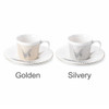 A coffee mug set featuring a golden and a silvery mug with corresponding saucers, both with a decorative design.
