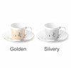 A ceramic coffee mug set in golden and silvery colour with matching saucers. Each mug features a simple design and handle.