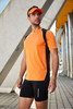A man in a fluorescent yellow and black running T-shirt, paired with black shorts and a visor, stands outdoors.