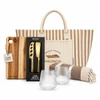 A tote bag with stripes, a wooden cheese board, a two-piece cheese set, two textured glasses, and a striped blanket.