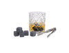 A whisky glass with amber liquid, grey whisky stones, and stainless steel tongs arranged nearby.