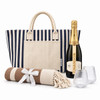 A striped tote bag, a bottle of Chandon Brut, two glasses, and a rolled blanket with a ribbon.
