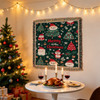 A festive tapestry blanket with red, green, and white designs, featuring Christmas trees and Santa, displayed in a cozy setting.