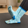 A pair of blue crew custom toe socks with a sailboat design and textured grips on the soles.