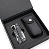A black multi-tool lies inside a black box with a textured case, featuring a silver tool with various functions.