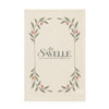 A cream-coloured tea towel featuring a floral design with green leaves and small pink accents, with a logo at the centre.
