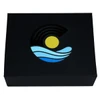 A black magnetic gift box featuring a colourful logo with a sun, waves, and circular patterns in blue and yellow.