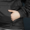 A black windbreaker featuring an elasticated cuff and a hand in the side pocket. Branding is visible on the jacket.