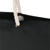 A black beach tote bag with a white rope handle and a silver eyelet. It features a simple, modern design.