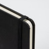 A4 daily diary in black with an elastic band closure and rounded corners. Features a textured cover and plain pages.