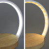 A wireless charging night light with a bamboo base, featuring a curved light design that shifts between white and warm yellow light.