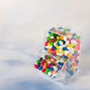 A clear dispenser filled with assorted coloured mini jelly beans, featuring vibrant hues of red, blue, green, yellow, and white.