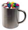 A stainless steel mug filled with assorted colourful mini jelly beans in various shapes. The mug has a logo.