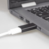 A black USB C adapter plugged into a laptop, with a white cable connected.