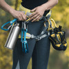 A drink bottle in silver aluminium is held alongside climbing gear, including carabiners and climbing shoes, in a natural setting.