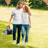 A striped cotton canvas cooler bag in navy and white, held by a couple walking in a grassy area.