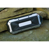 A rugged, waterproof Bluetooth speaker in black and silver, resting on a rock surface.