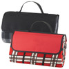 A picnic rug with a red and plaid design, featuring a black carrying handle and foldable design.
