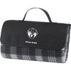 A picnic rug in black and grey, featuring a carrying handle and a logo on the front.