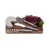 A stainless steel cheese knife set on a wooden board, featuring a cheese wedge and a bunch of red grapes.