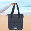 A black laptop tote bag made from recycled material, featuring two handles and a zipper closure, being held by a person.