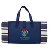 A navy blue picnic rug with a striped pattern and carrying handles, featuring a logo on the front.