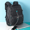 A black and grey backpack with multiple compartments, featuring a logo and a charging cable connected to a device.
