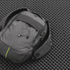 A grey laptop backpack featuring a main compartment, adjustable straps, and a logo, set against a textured black background.