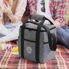 A drink bottle cooler bag made of grey recycled felt, featuring black straps and a logo, on a picnic blanket.